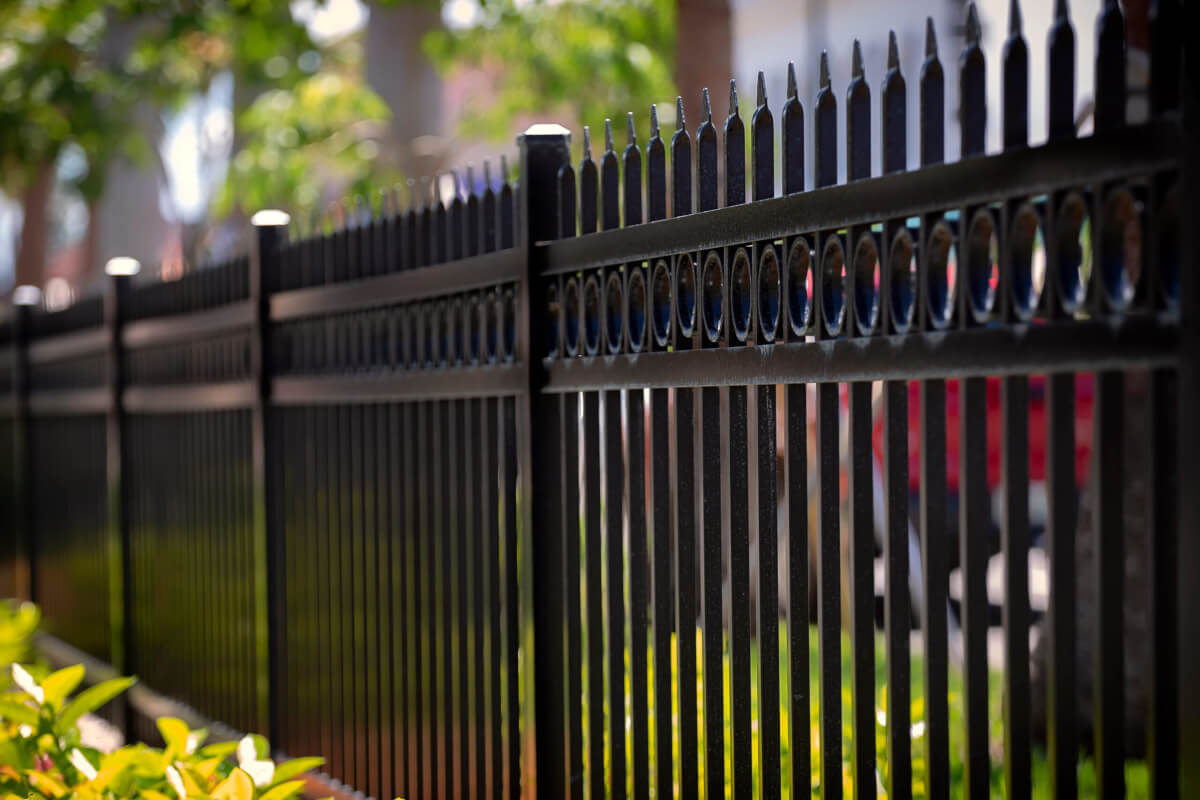 Black wrought iron OR ALUMINUM fence with decorative accents in a landscaped yard.