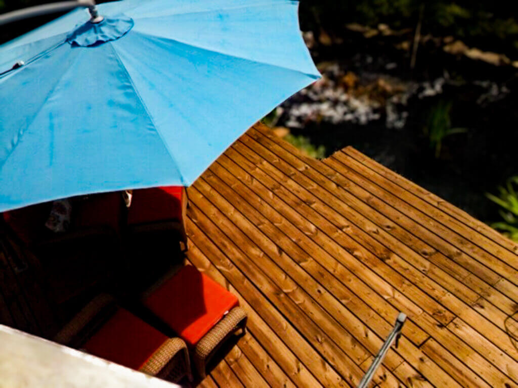 Customer review photo of a beautifully pressure-washed and stained backyard wooden patio overlooking a sparkling pool.