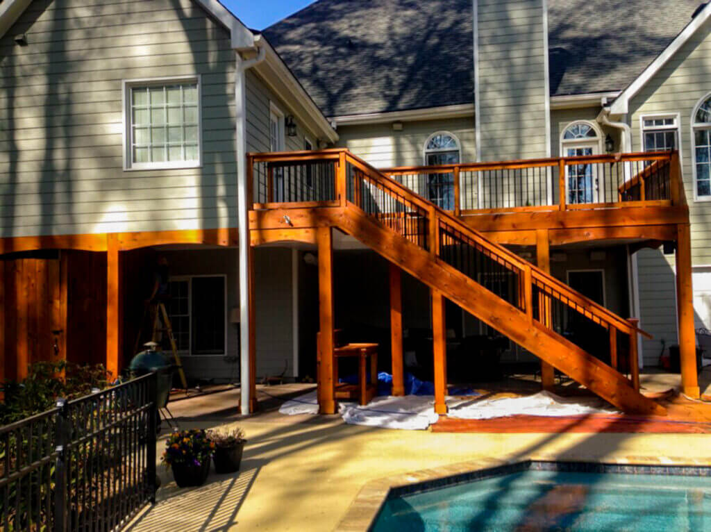 Customer review photo of a beautifully pressure-washed and stained backyard wooden patio overlooking a sparkling pool.