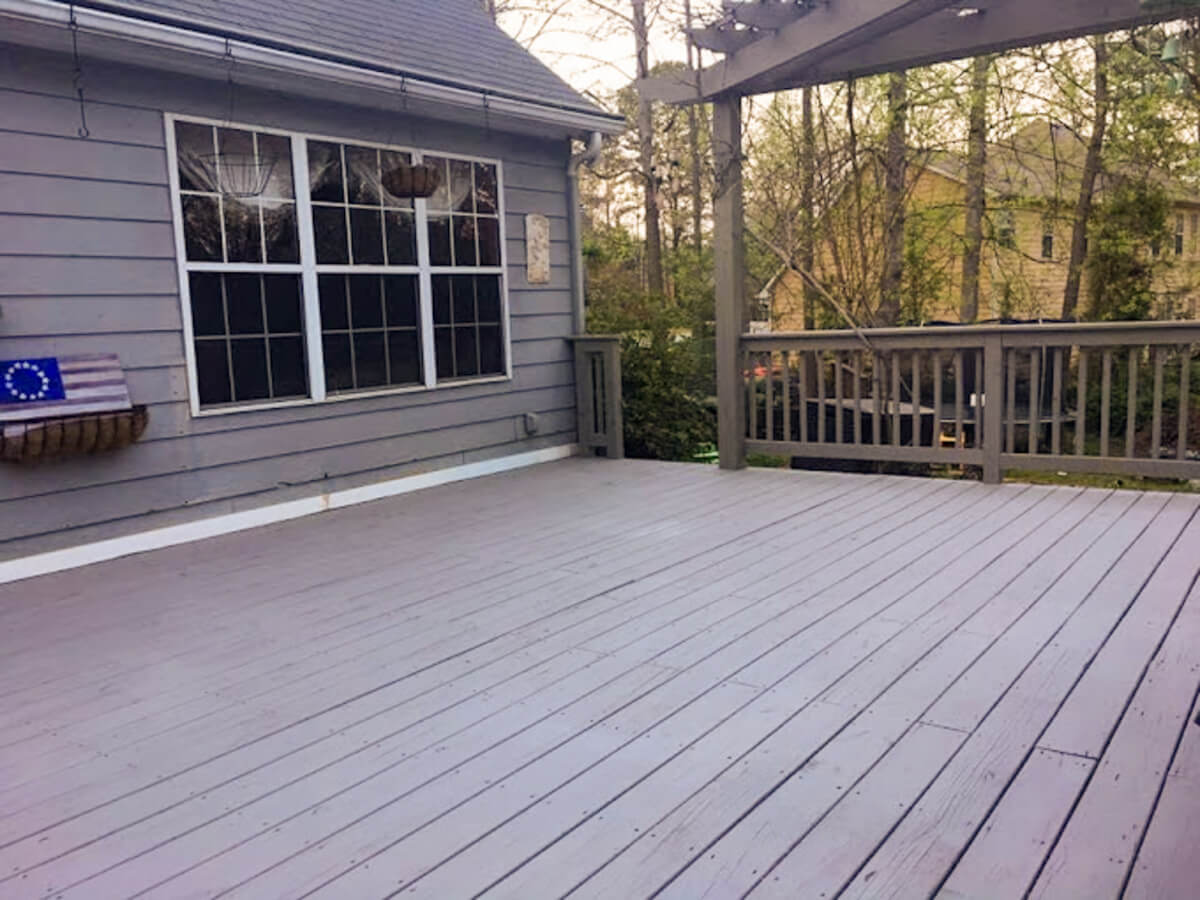 Beautifully hand-stained wooden deck with wrought iron railing and pergola after a professional deck pressure washing service