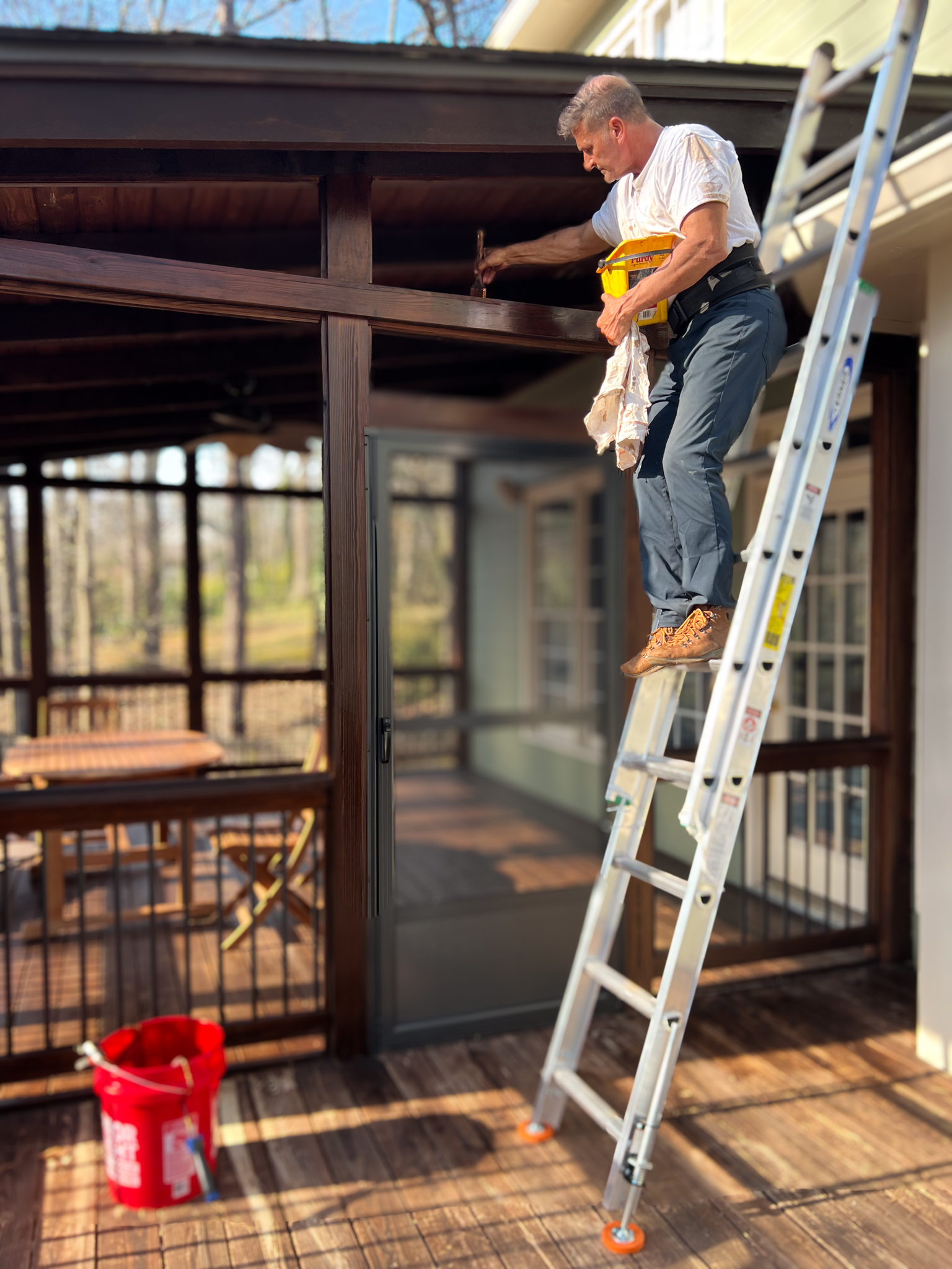 Expert Deck Staining & Restoration Services - MAN HAND STAINING THE TOP OF AN EXTERIOR DOOR FRAME