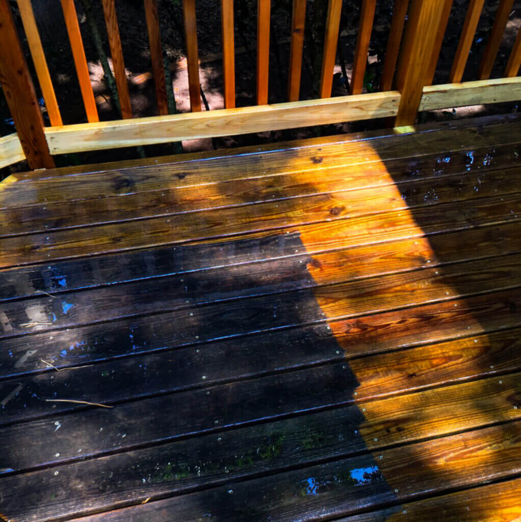 Wooden deck repair and pressure washing in action—new wood additions visible with a clear line between dirty and freshly washed wood.