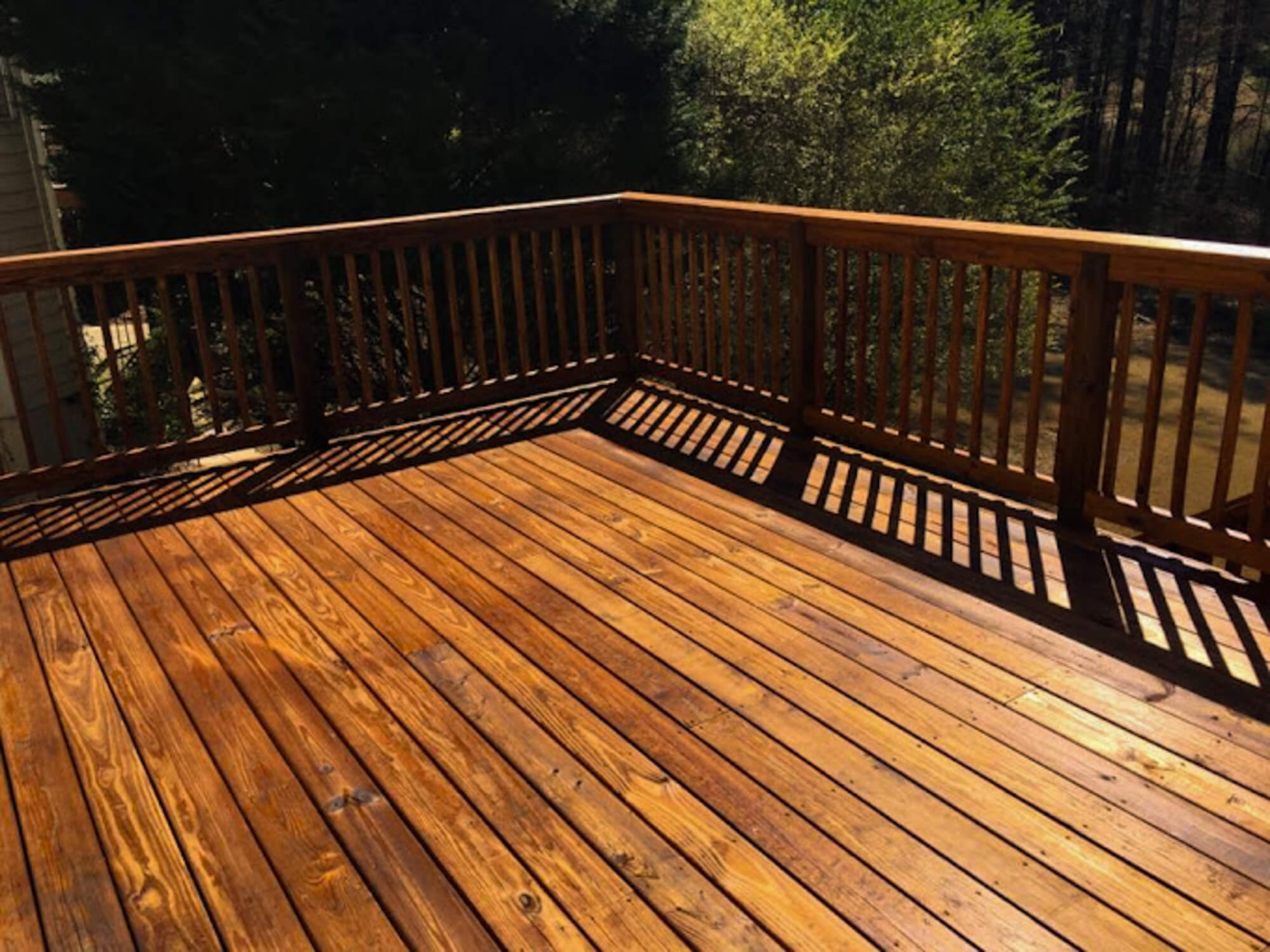 Freshly stained wooden deck and railing with a rich, even finish, enhanced by expert back-brushing for long-lasting protection.