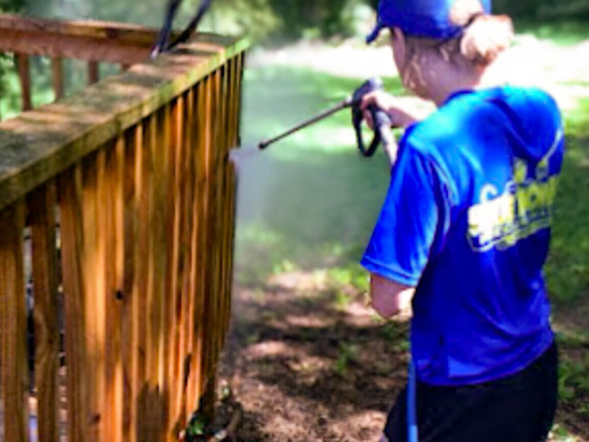 female BLUE MONKEY worker PRESSURE WASHING A WOODEN DECK BEFORE A HAND STAIN AND SEAL SERVICE