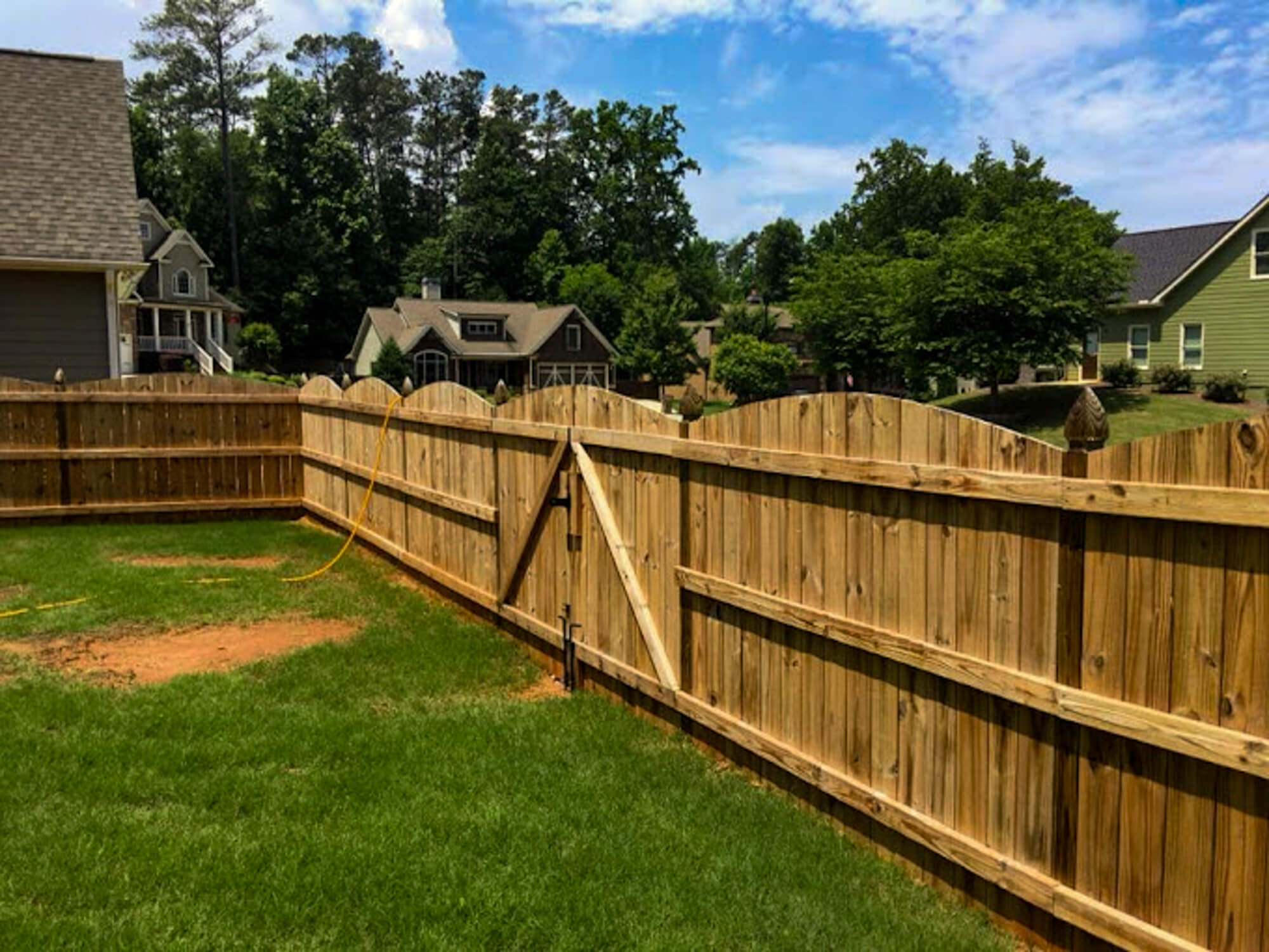 Freshly pressure-washed wooden fence in a backyard, prepped for wood staining and sealing to enhance durability and natural beauty.