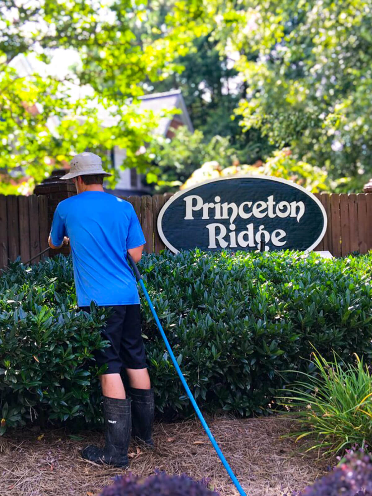 Commercial pressure washing service in action for neighborhood fence and sign Professional cleaning results.