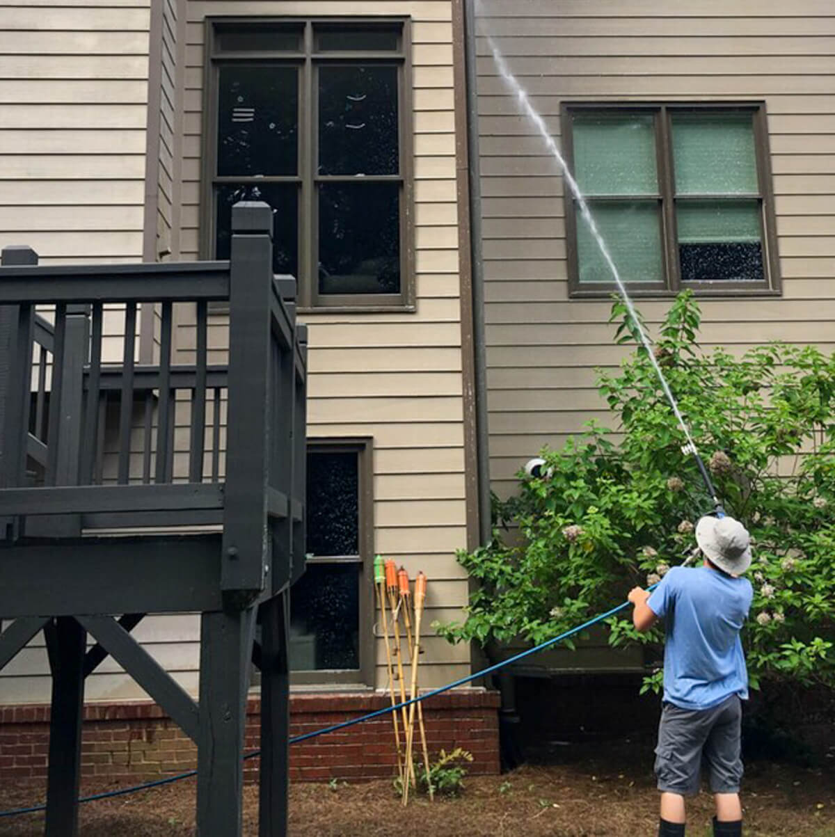 Blue Monkey Pressure Washing tech cleaning the siding of a large home’s backyard during an exterior home pressure washing service.
