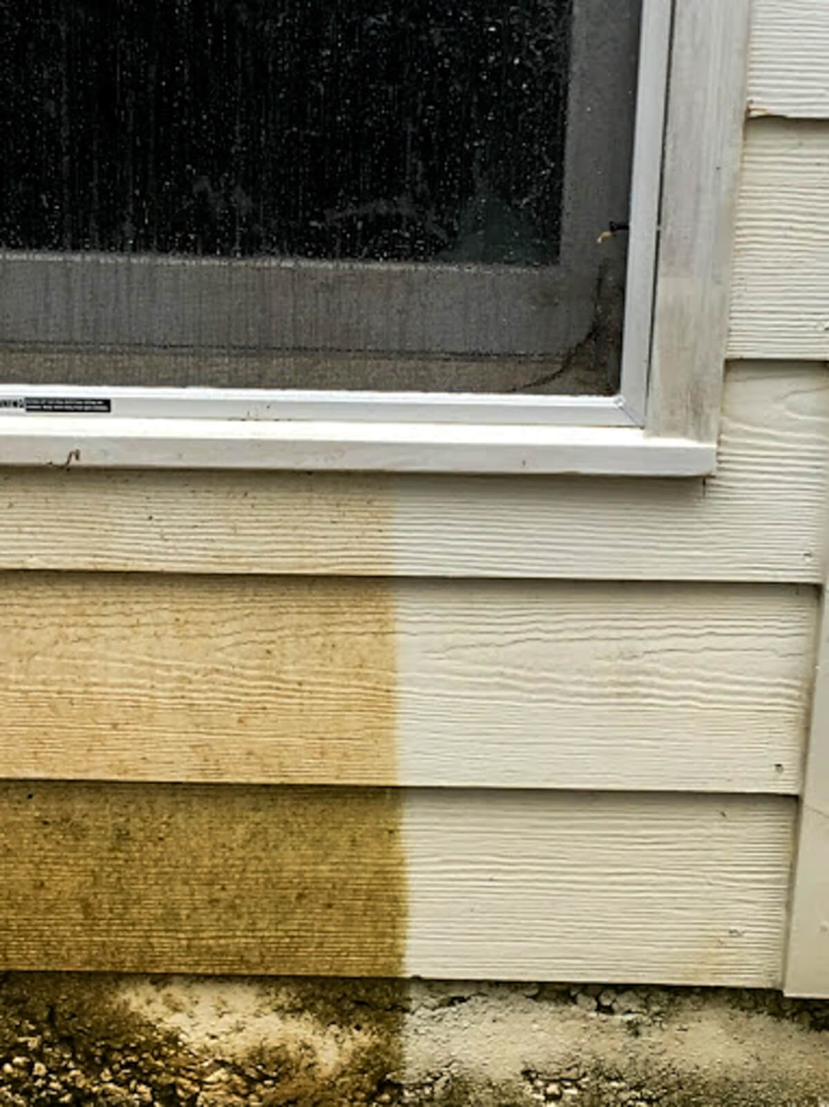 Wood siding being pressure washed, showing a clear contrast between the dirty surface and freshly cleaned exterior.