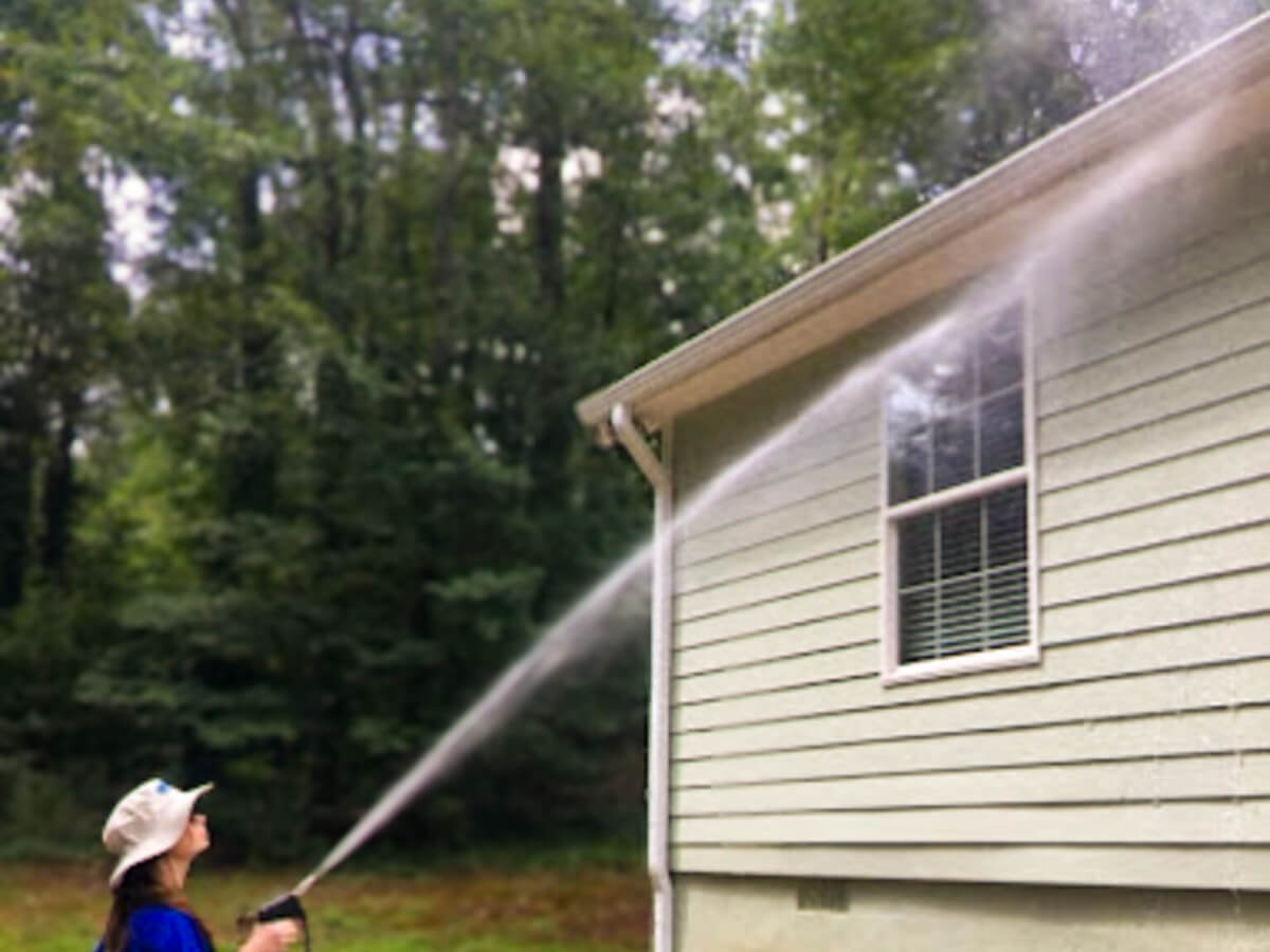 Blue Monkey Pressure Washing tech cleaning soffits below gutters during a professional exterior gutter cleaning service.