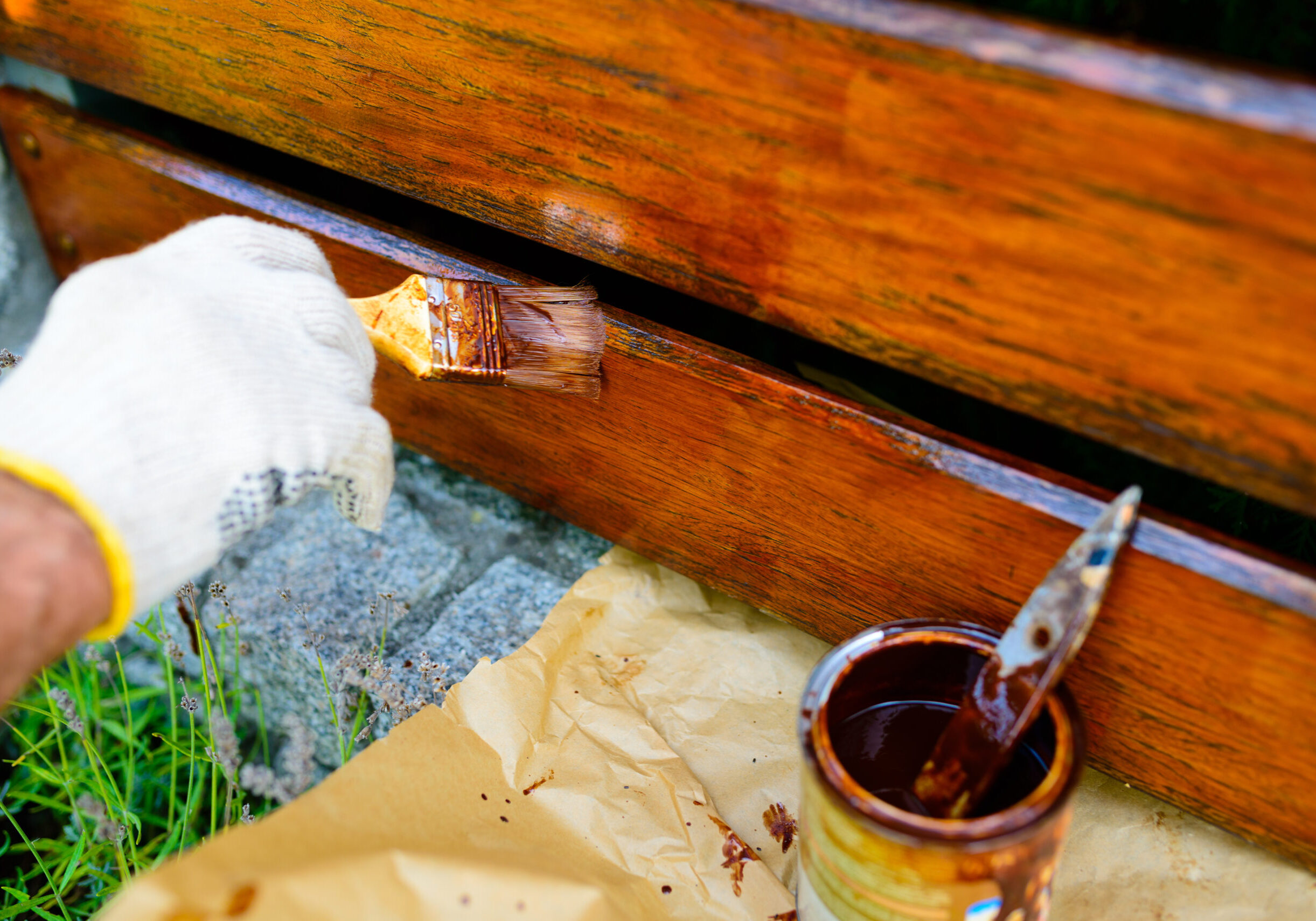 Professional staining a wooden backyard fence in natural sunlight. fence repair, fence restoration, fence resurfacing