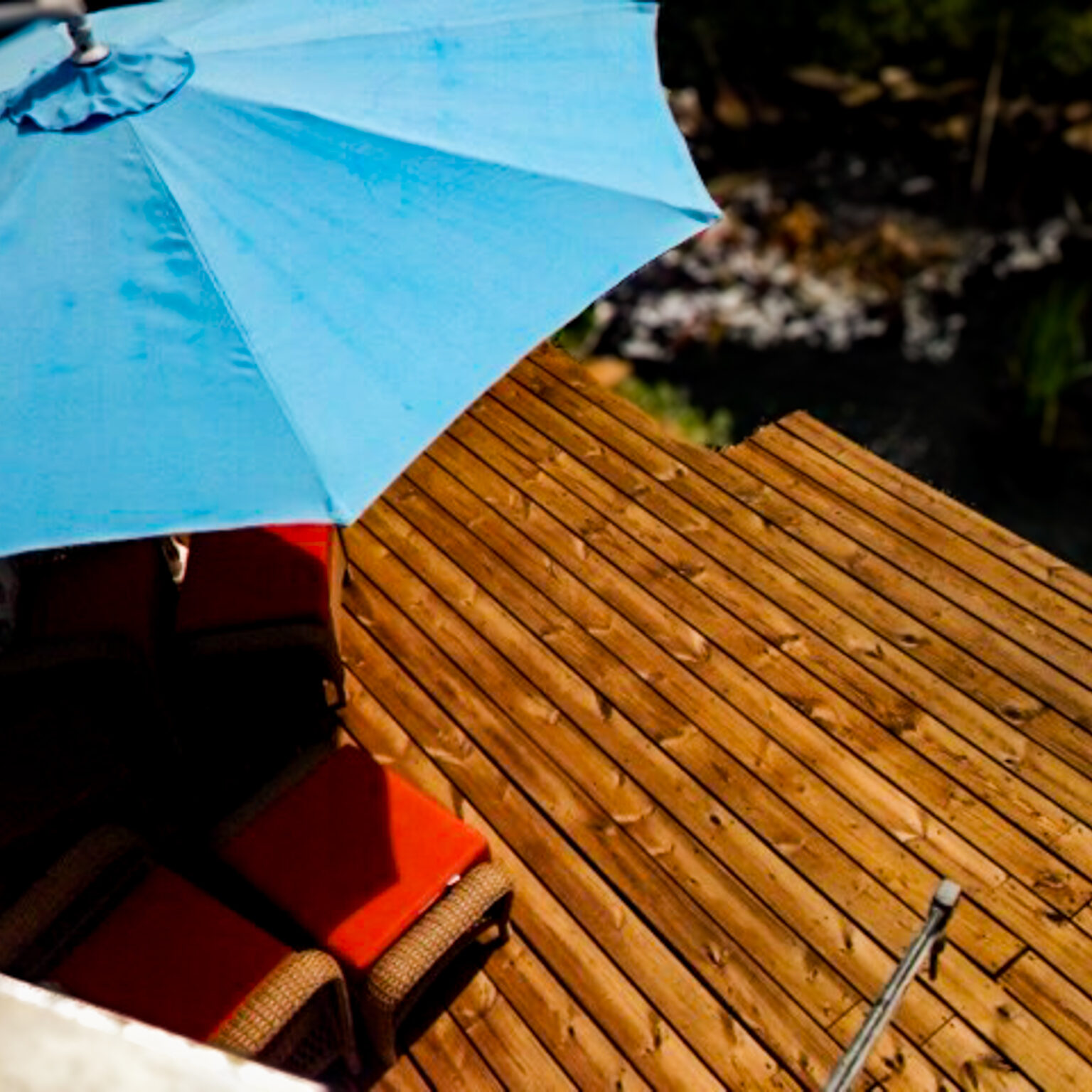 Customer review photo of a beautifully pressure-washed and stained backyard wooden patio overlooking a sparkling pool.