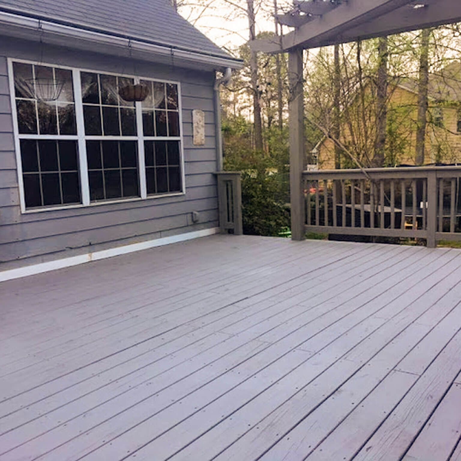 Beautifully hand-stained wooden deck with wrought iron railing and pergola after a professional deck pressure washing service