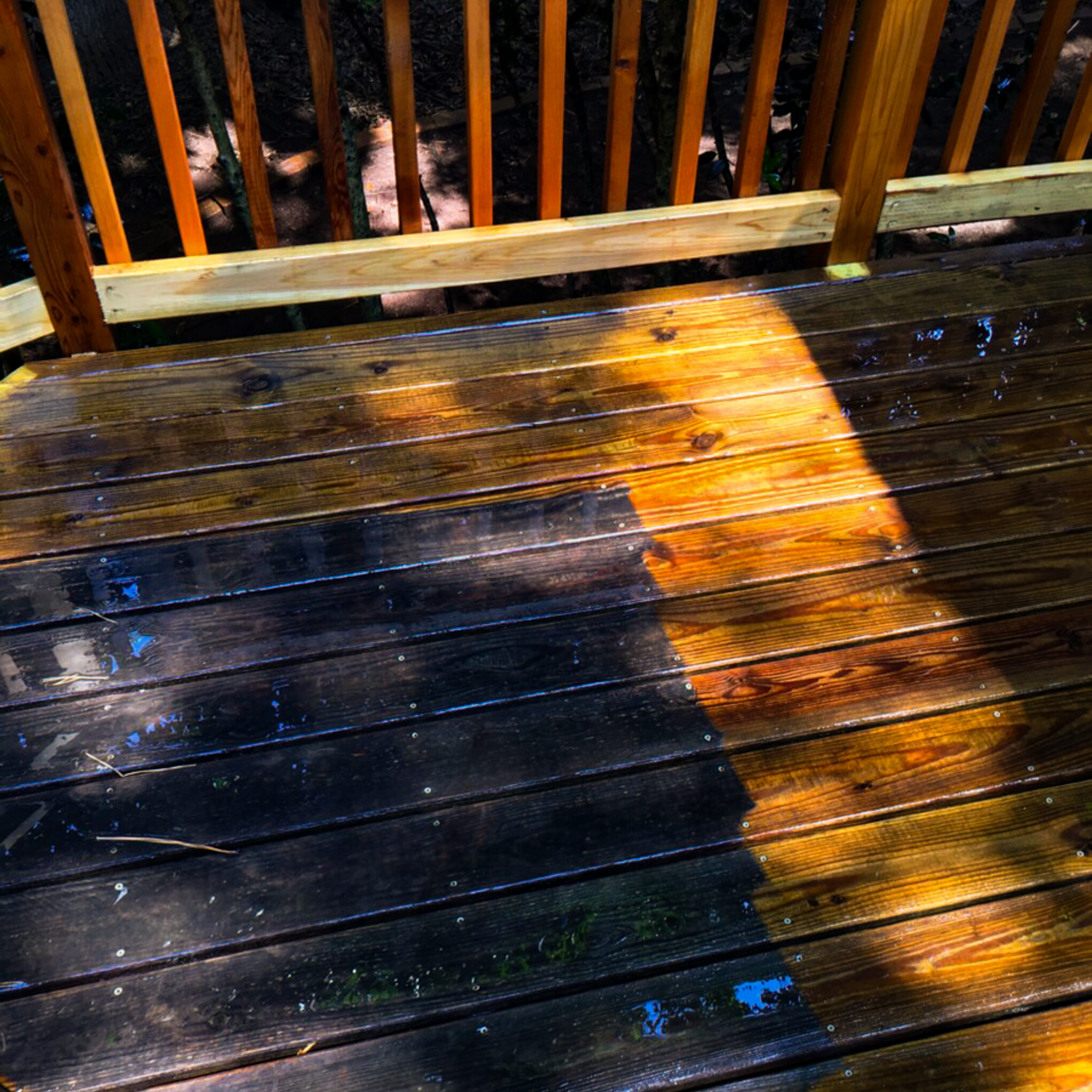 Wooden deck restoration, deck resurfacing, and deck repair with pressure washing in action—new wood additions visible with a clear line between dirty and freshly washed wood.