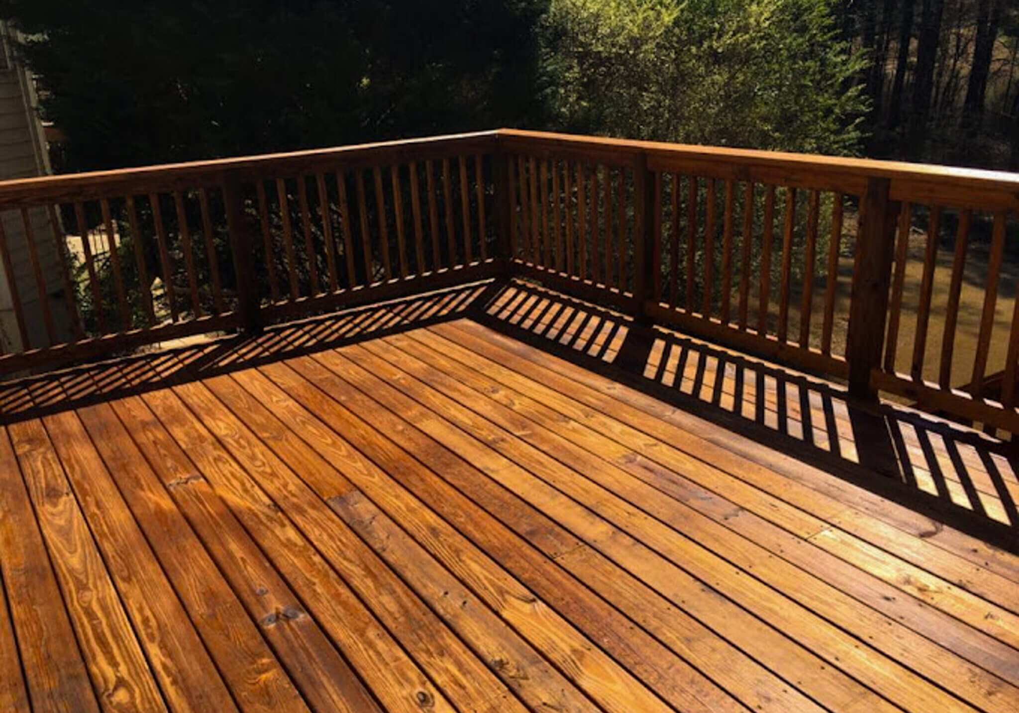Freshly stained wooden deck and railing with a rich, even finish, enhanced by expert back-brushing for long-lasting protection.